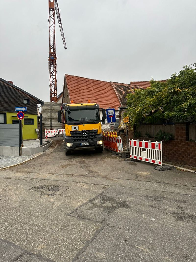 Godec-LKW in einer engen Baustellenstraße mit Absperrungen und Kran